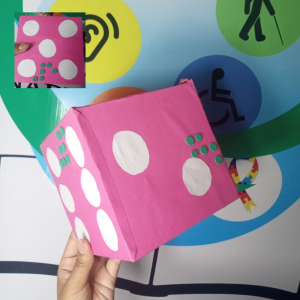 Dado de aprendizagem braille, no qual detém relevos e pontos para que o indivíduo que utilizá-lo consiga determinar os números que caírem no dado